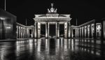 A black and white photo of a brandenburg gate at night