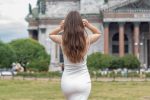 Female back with long curly brunette hair on summer park background