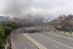 People gather near rising smoke on a street