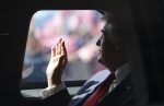 US President Donald Trump waves from his official vehicle, The Beast