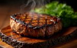 Grilled steak on a wooden board with green leaves