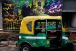 An auto rickshaw parked near a picture poster of Brazil's soccer team